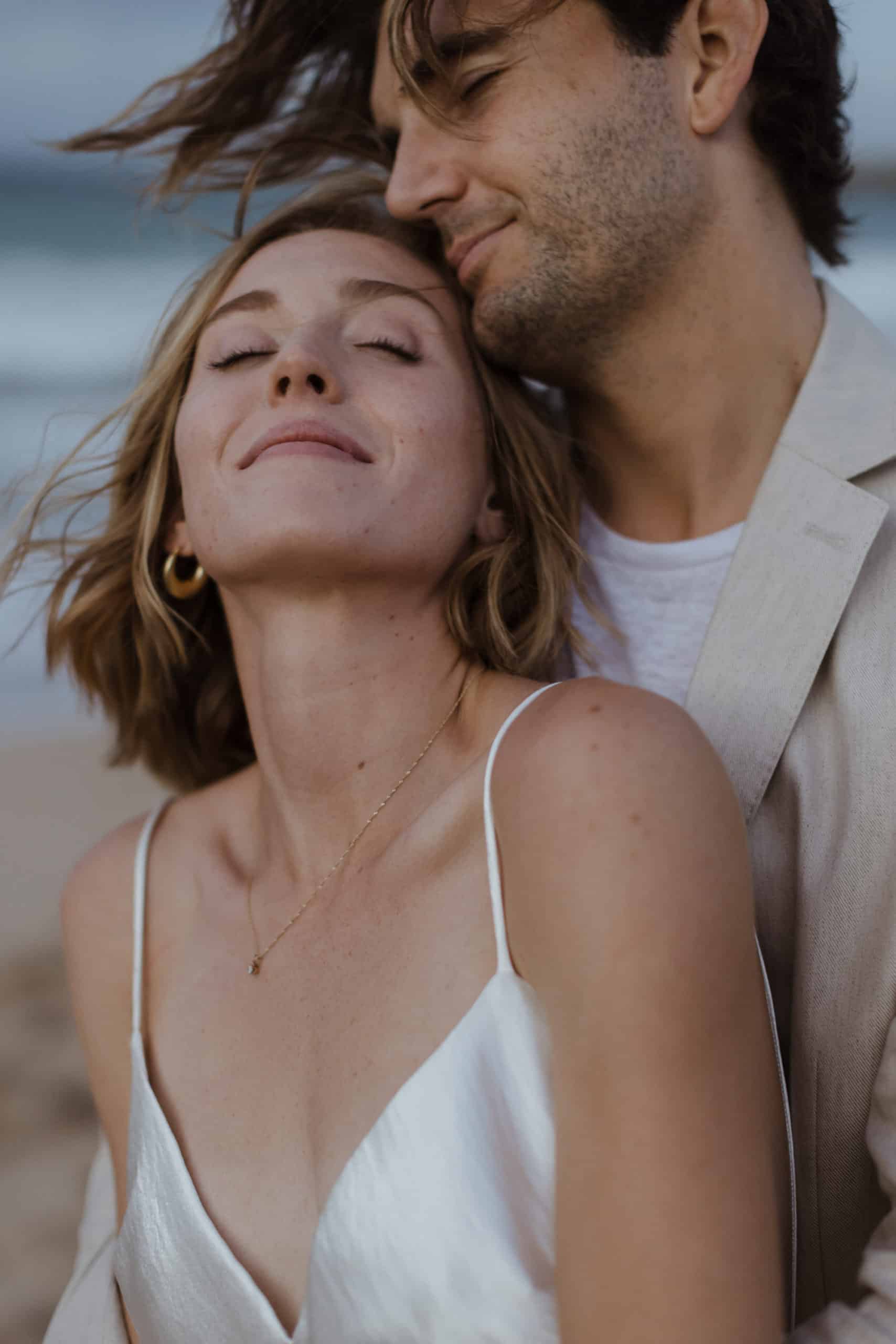 A couple is standing next to each other on the beach, after their ceremony to elope in Maui.