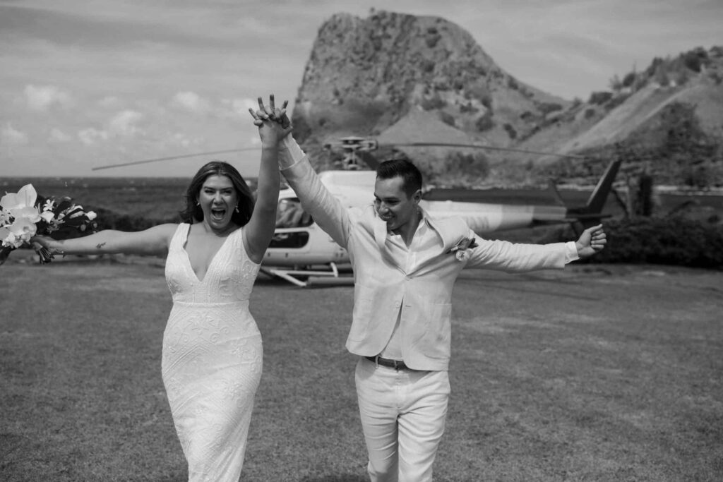 A bride and groom running and cheering about getting married.