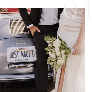 Couple in wedding attire stands by a vintage Porsche with a "JUST MAUI'D" license plate. The bride holds a bouquet.