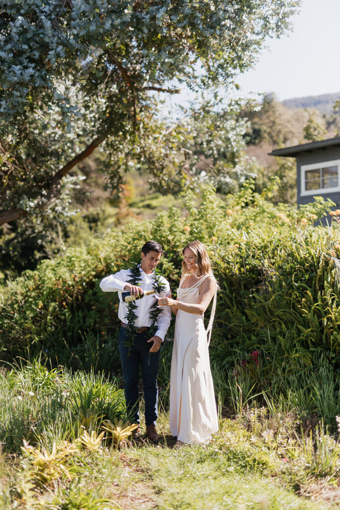 Roam Elopements, Maui Elopements, Couple celebrating elopement, pouring champagne outdoors.