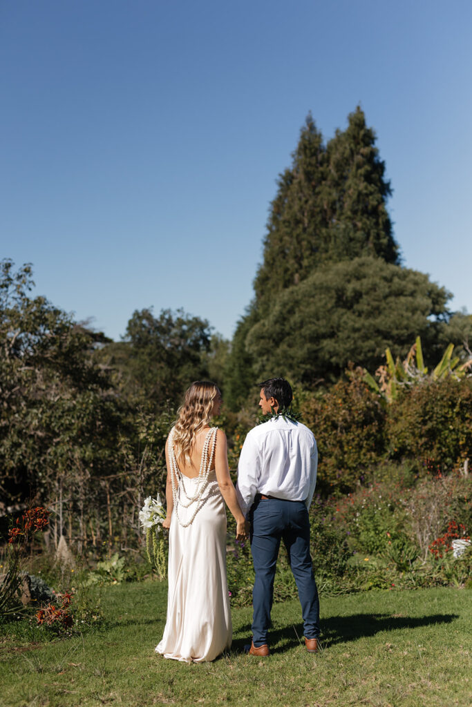Roam Elopements, Maui Elopements, Bride and groom holding hands in a garden during their elopement.