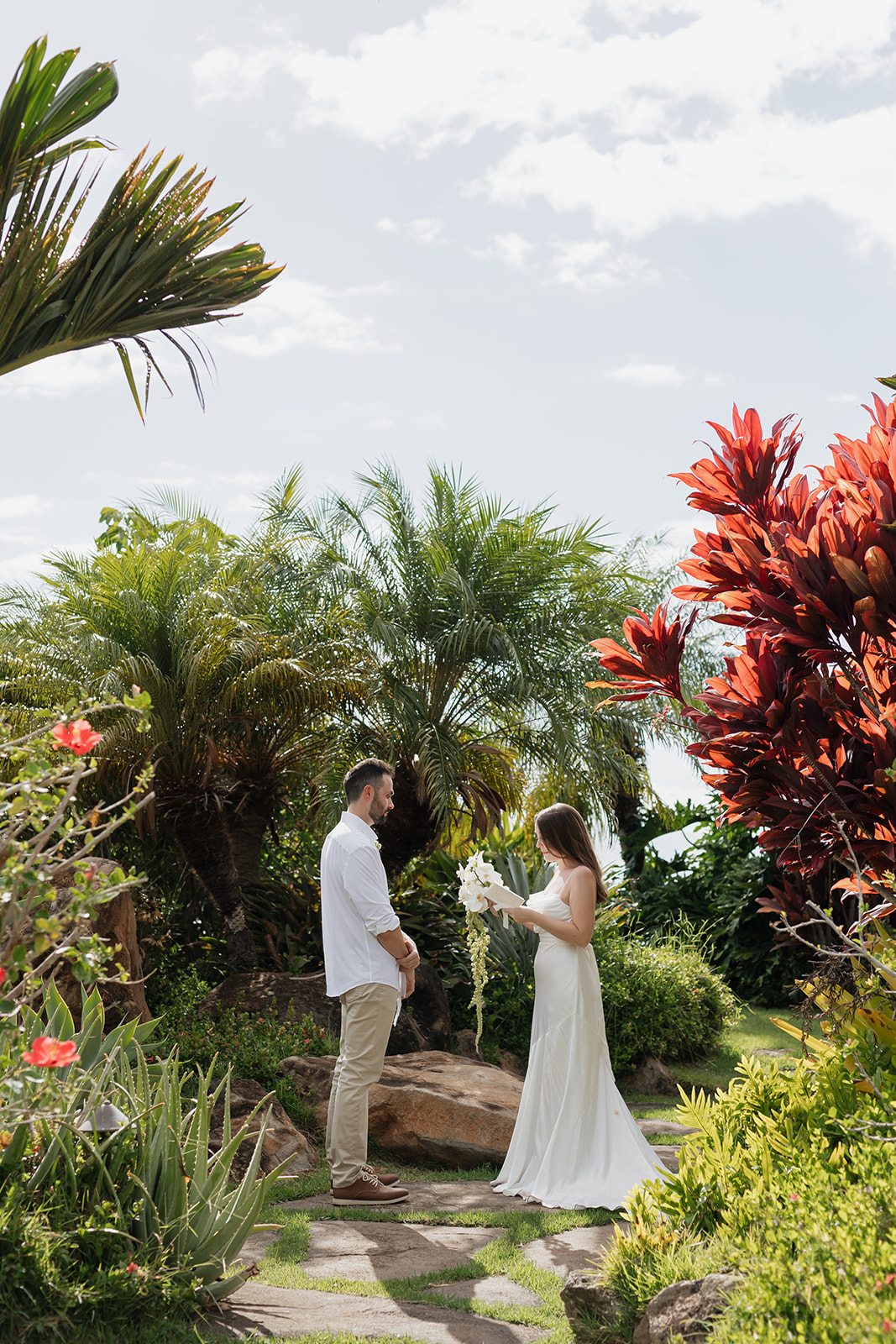 Roam Elopements, Maui Elopements, Elopement scene: Bride with bouquet and groom in a garden setting.