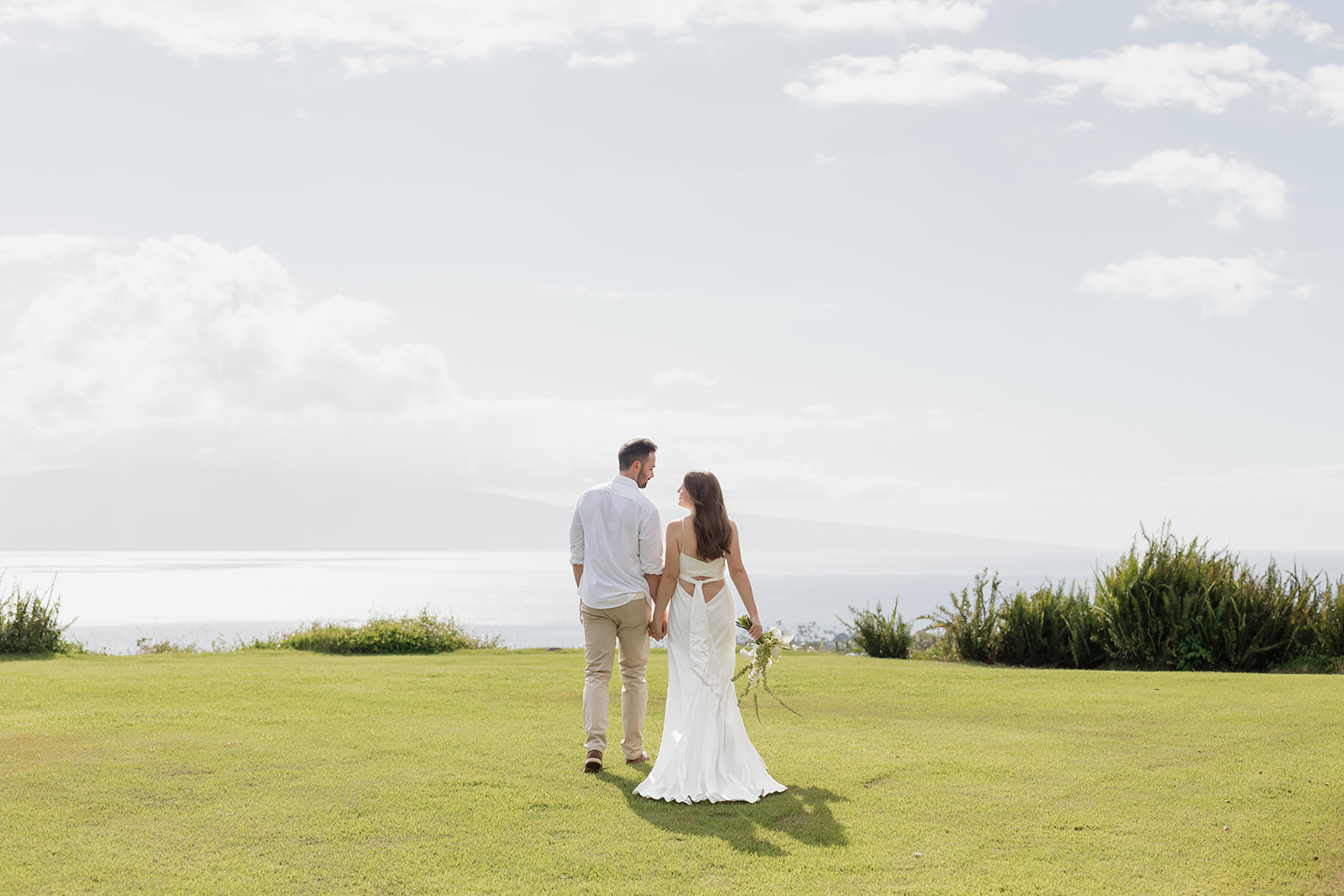 Roam Elopements, Maui Elopements, Couple walking on green grass towards the ocean. Elopement location.