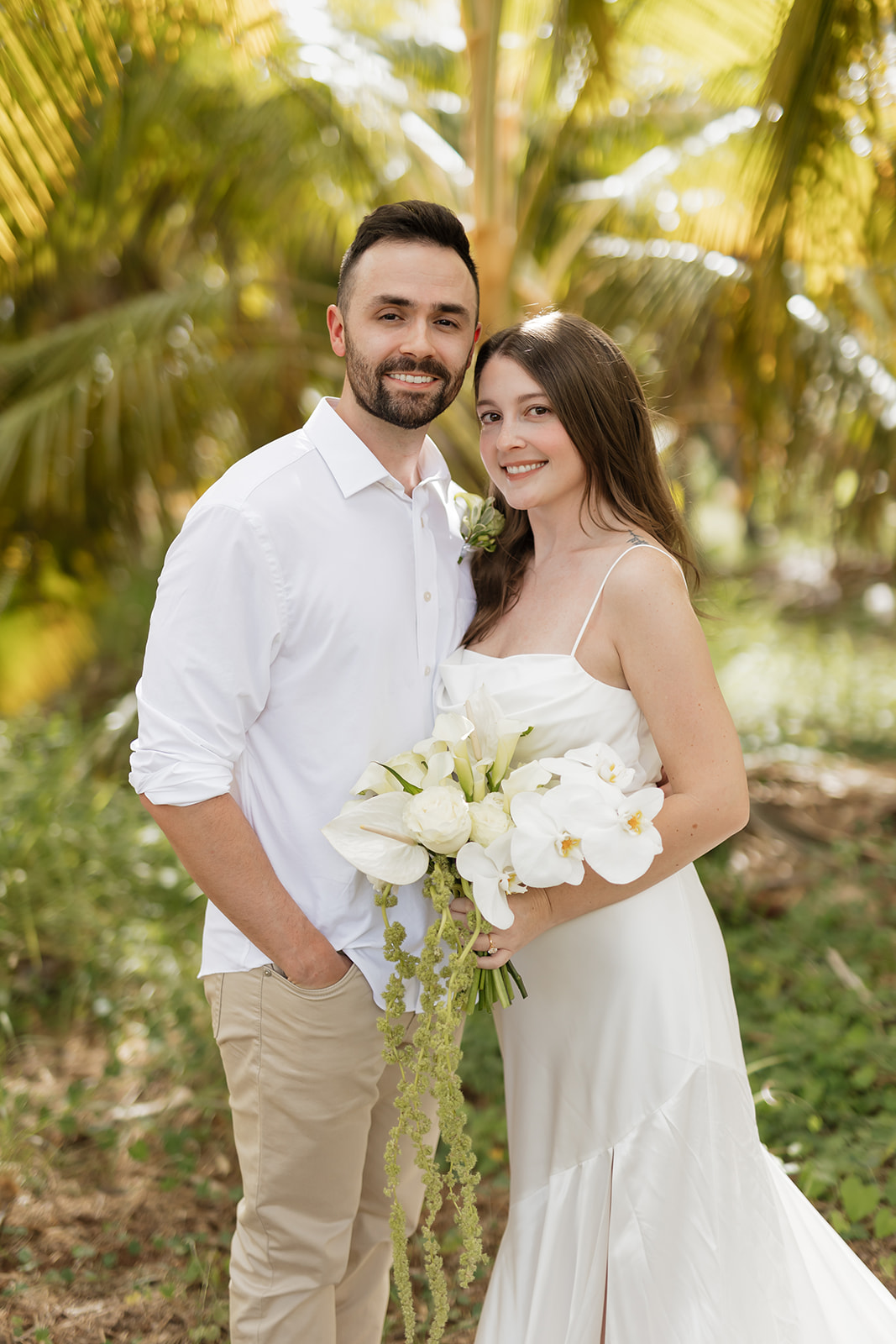 Roam Elopements, Maui Elopements, Happy couple eloping, posing outdoors with white flower bouquet. Elopement location guide.