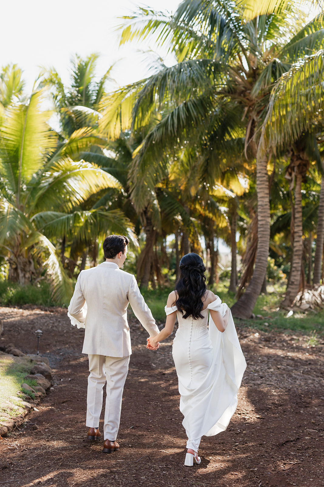 Roam Elopements, Maui Elopements, Eloping couple walking hand-in-hand through a palm tree grove.
