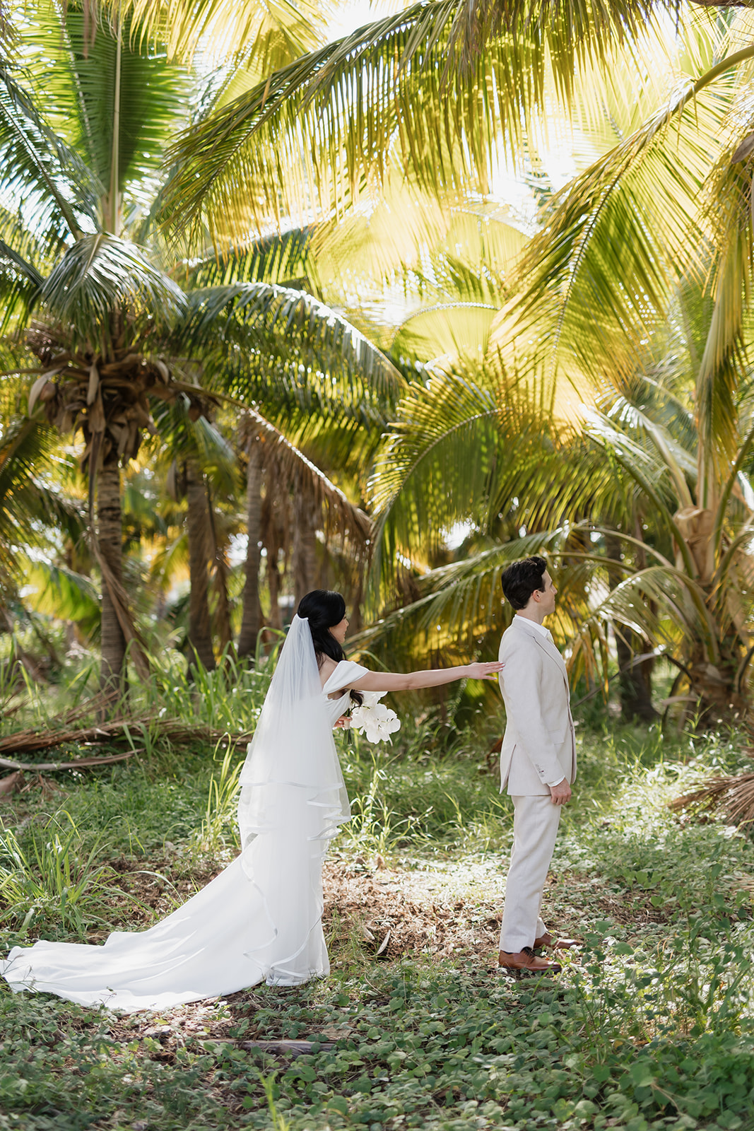 Roam Elopements, Maui Elopements, Bride touches groom's shoulder in tropical elopement location. Palm trees create a romantic backdrop.