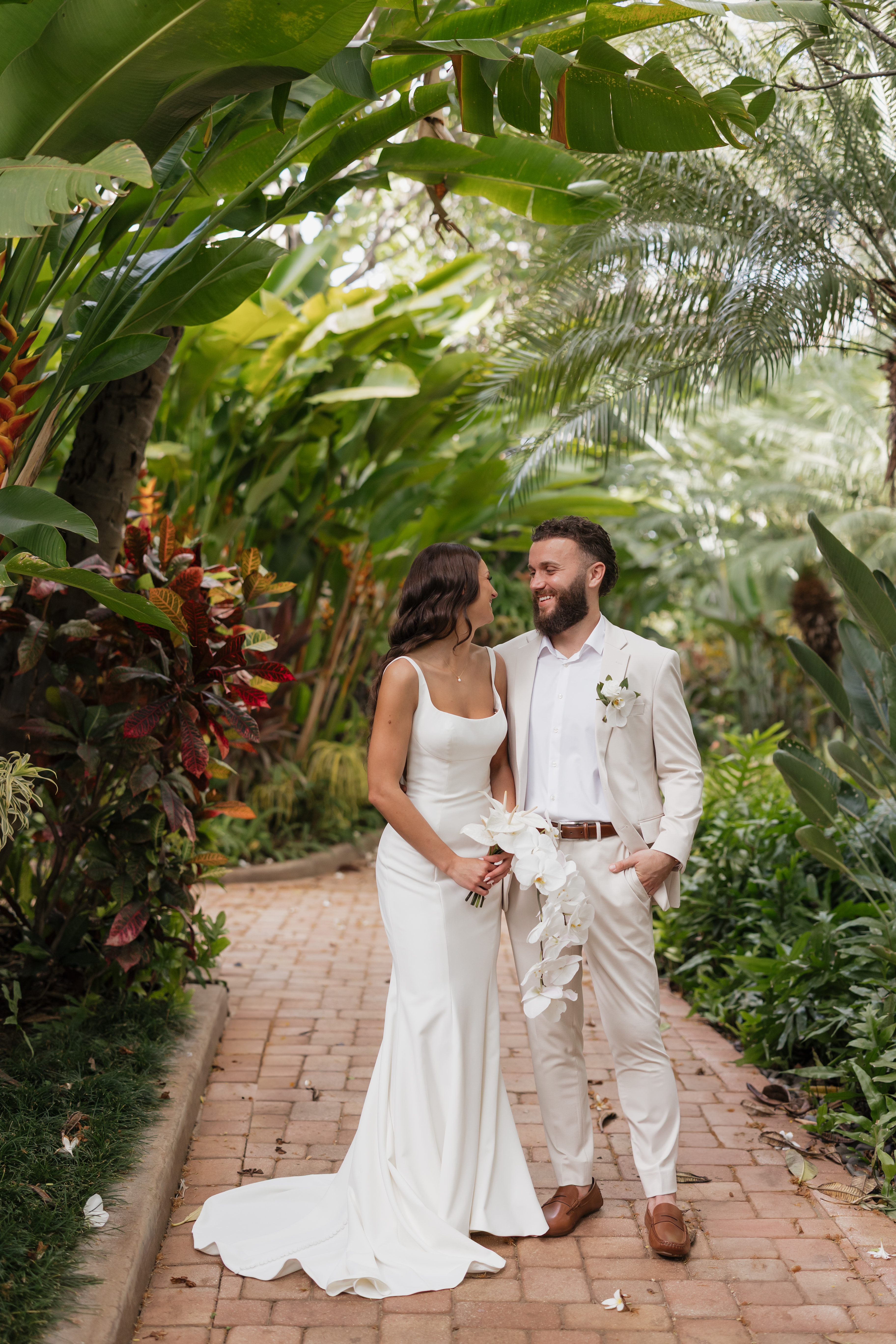 Roam Elopements, Maui Elopements, Happy couple in wedding attire, embracing amidst lush tropical foliage. Wailea elopement.