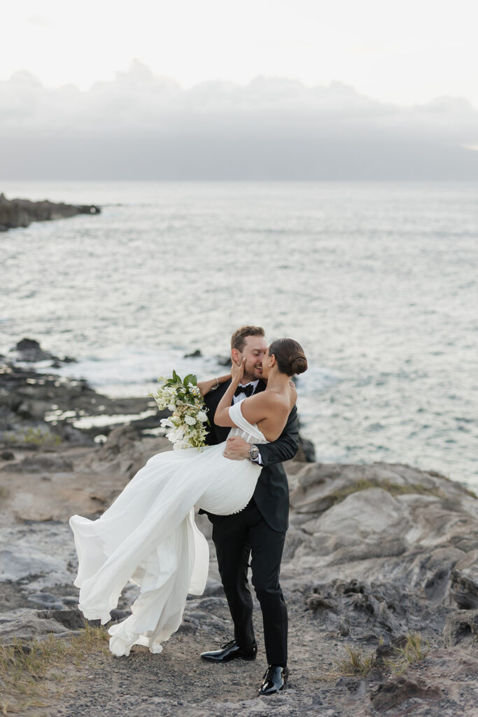 Roam Elopements, Maui Elopements, Groom carrying bride in white dress during West Maui elopement. Serene ocean view.