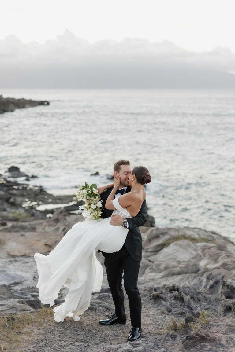 Roam Elopements, Maui Elopements, Groom carrying bride in white dress during West Maui elopement. Serene ocean view.