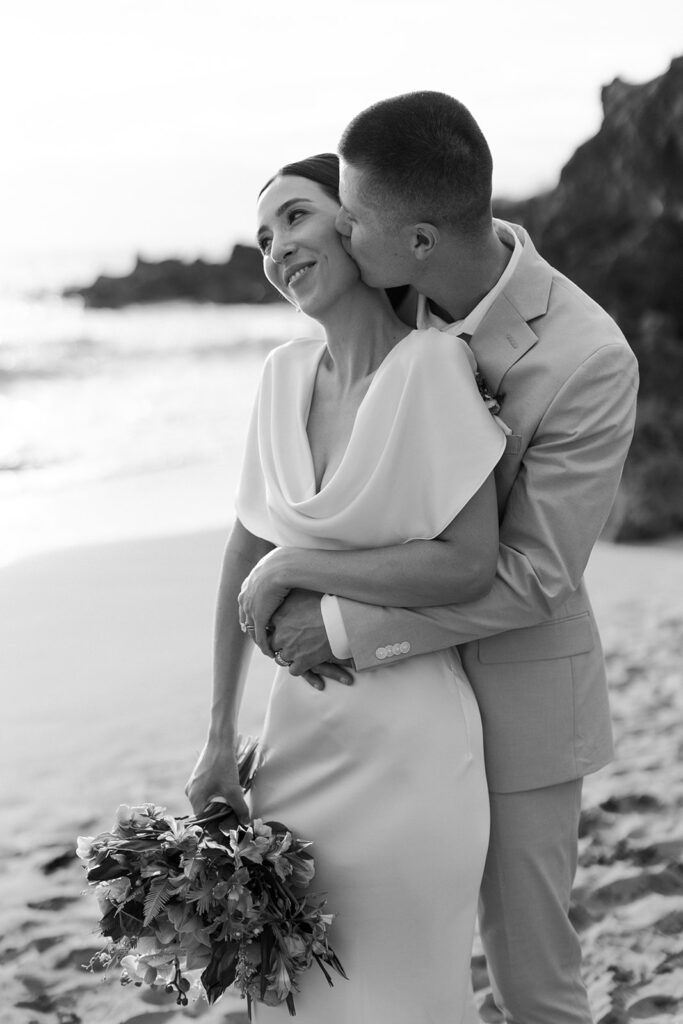 Roam Elopements, Maui Elopements, Bride and groom embrace on a beach during their micro wedding.